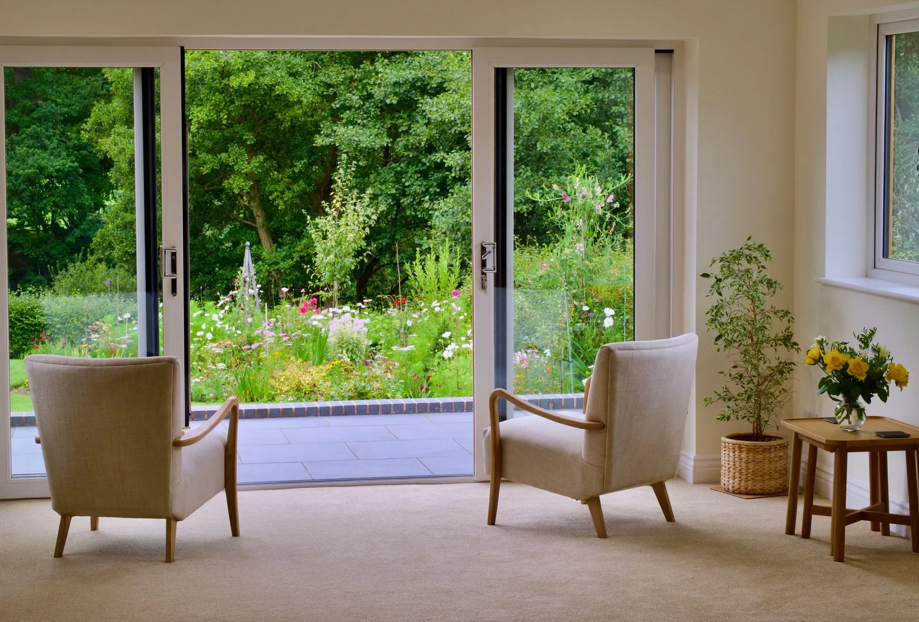 A finished single-storey extension with wide glazed doors open onto a flowering garden