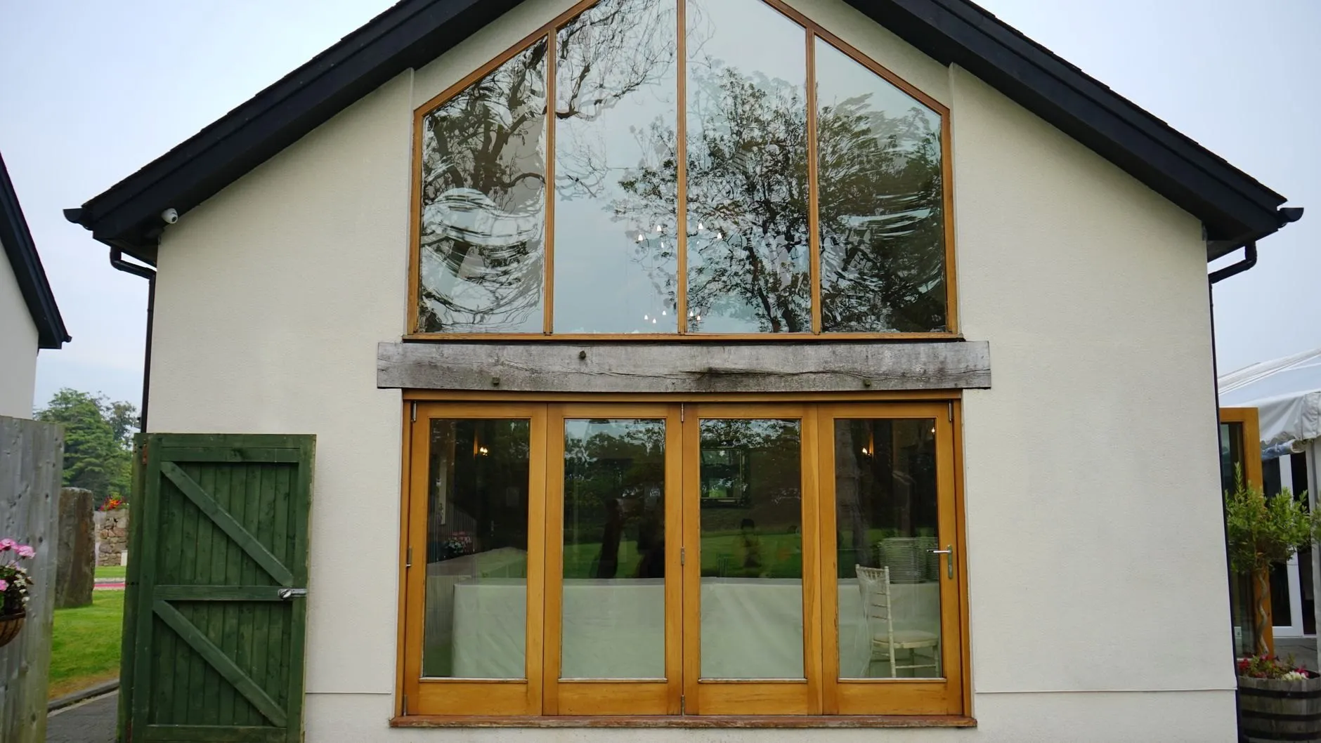 A two-storey rendered gable extension with a glazed apex and oak-framed folding doors below
