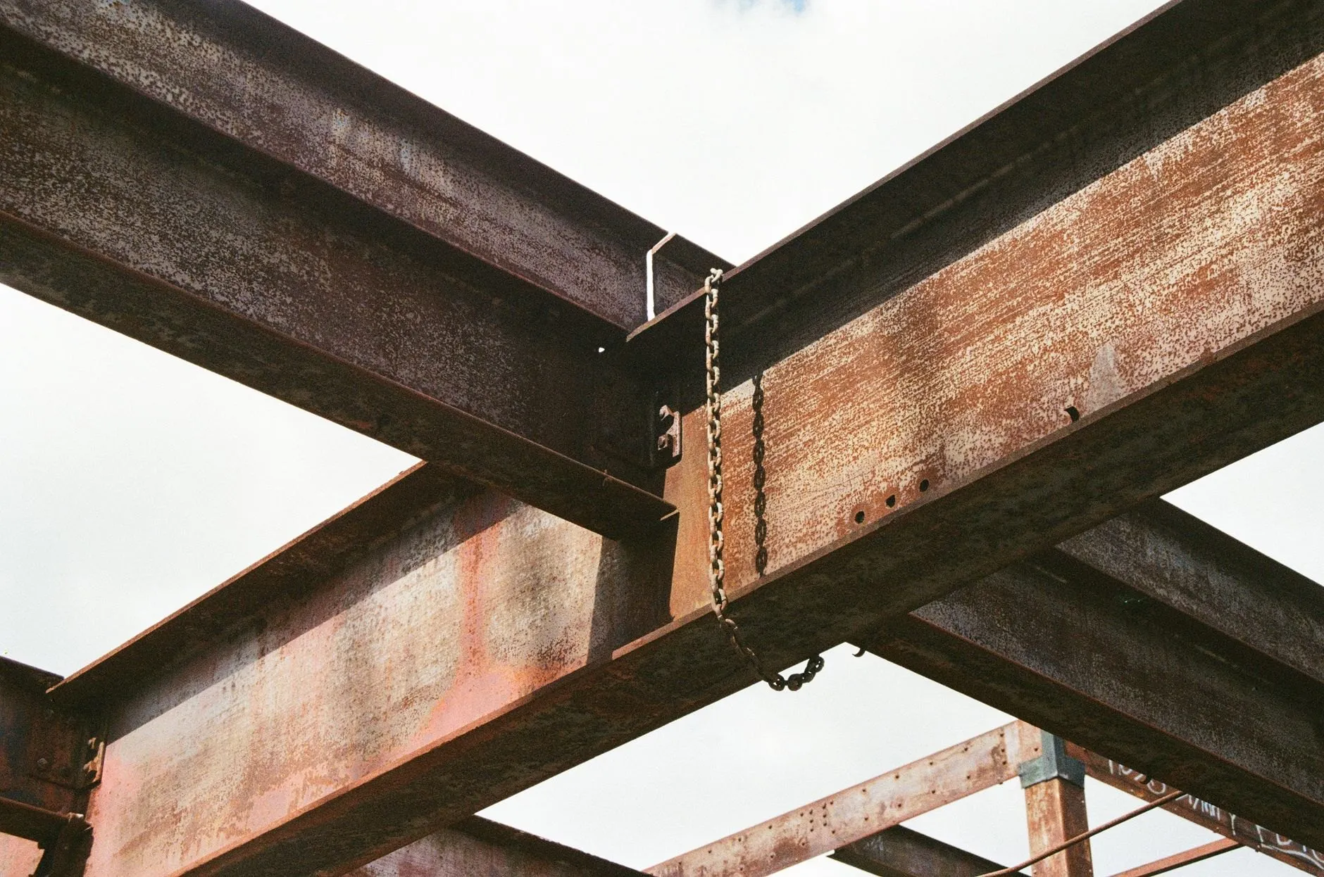 Two steel beams crossing overhead against a pale sky